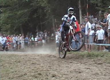 Pro mtn bike racer at the NORBA finals at Mount Snow doing a wheelie with a flat
