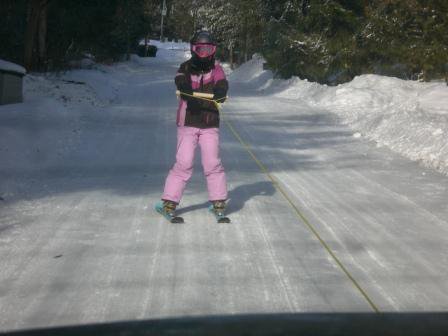 Little sister skiing behind car